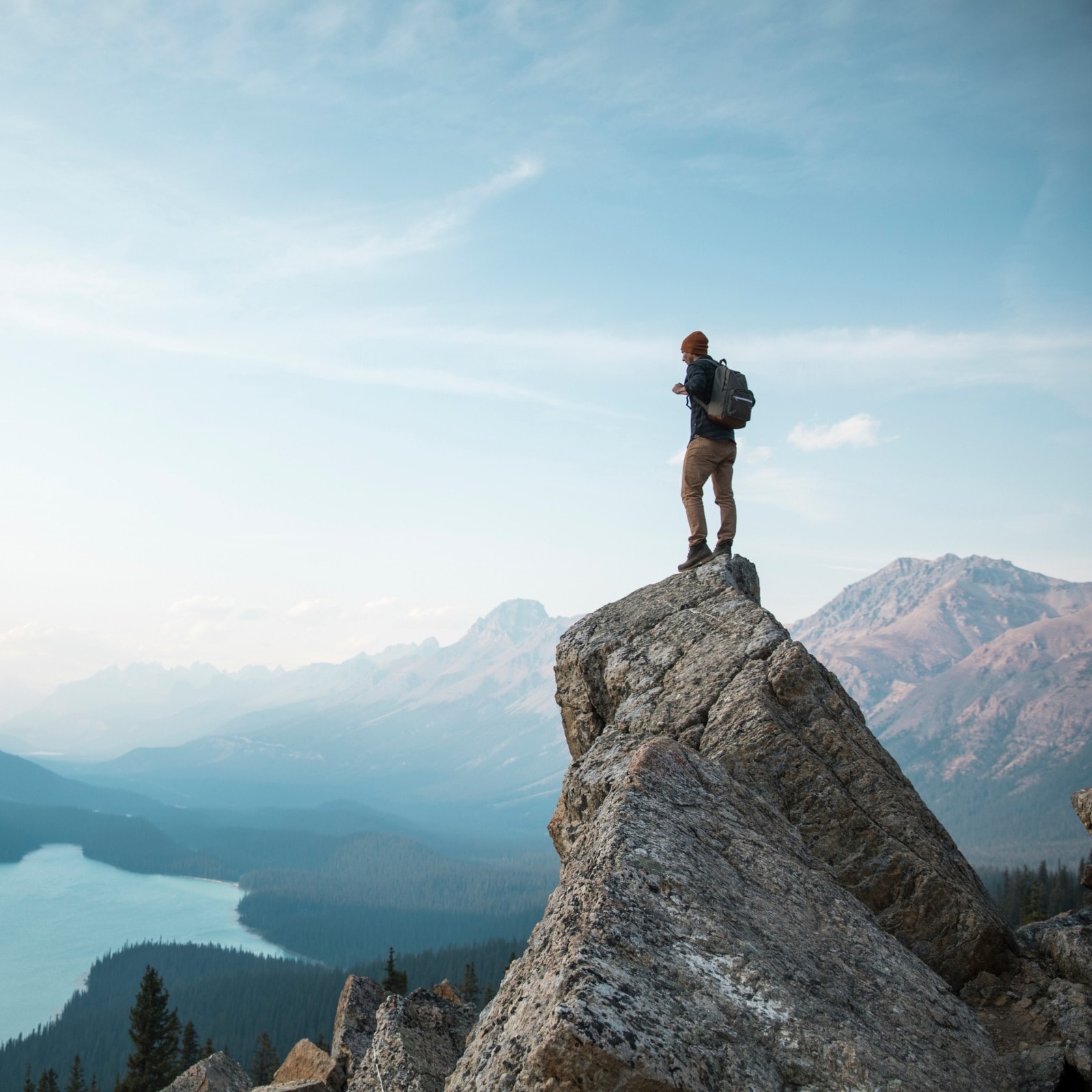 Hiker standing on a mountain peak overlooking a turquoise lake — representing the journey to financial freedom